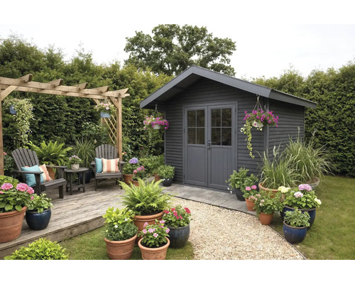 Abri de jardin moderne en bois anthracite avec double porte, terrasse en bois avec coin salon, pergola et nombreux pots de fleurs.