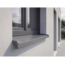 Appui de fenêtre extérieur en aluminium monté sur une façade crépie sous une fenêtre.