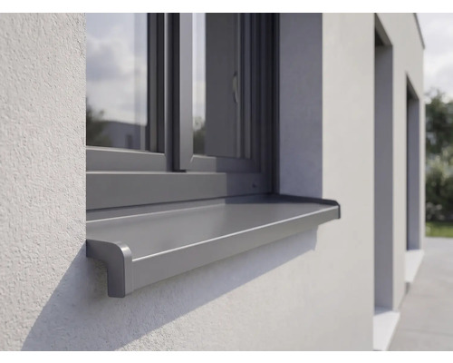 Appui de fenêtre extérieur en aluminium monté sur une façade crépie sous une fenêtre.