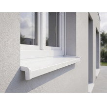 Appui de fenêtre extérieur blanc en plastique installé sous une fenêtre sur une façade en crépi clair.