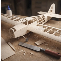 Maquette d avion en bois en cours de construction sur un établi avec une scie fine et de la colle à bois.