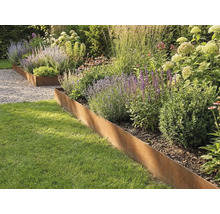 Beetbegrenzung aus Cortenstahl trennt Rasenfläche von einer bepflanzten Rabatte mit Gräsern und Stauden.