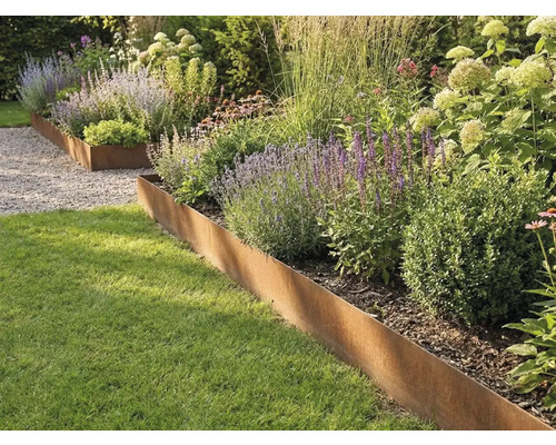 Bordure de jardin en acier Corten séparant la pelouse d une plate-bande plantée de graminées et de plantes vivaces.