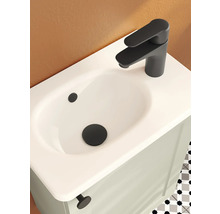 Lavabo avec mitigeur noir mat et bonde sur un meuble sous-lavabo clair dans une salle de bain moderne.