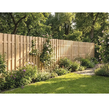 Hoher Holzzaun aus vertikalen Latten mit abgerundeten Köpfen in einem sonnigen Garten mit Rasen, Blumen und Bäumen.