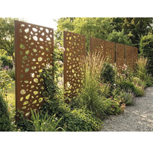 Paroi de séparation en acier Corten avec motif organique perforé dans un jardin avec des vivaces et des graminées.