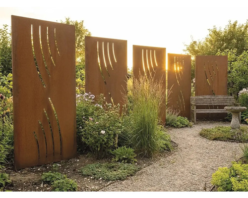 Plusieurs parois de protection visuelle en acier Corten couleur rouille avec découpes décoratives dans un jardin avec chemin de gravier.