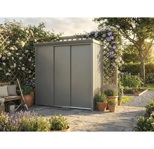 Armoire de jardin moderne en métal avec portes coulissantes sur une terrasse en pierre dans un jardin lumineux et organisé avec fleurs et plantes.
