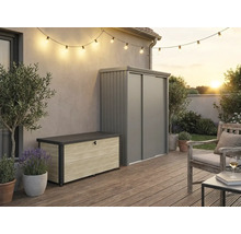 Espace extérieur avec coffre de rangement aspect bois et armoire de jardin en métal gris sur une terrasse en bois avec guirlande lumineuse.