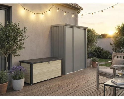 Espace extérieur avec coffre de rangement aspect bois et armoire de jardin en métal gris sur une terrasse en bois avec guirlande lumineuse.