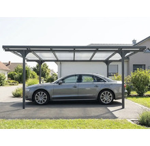 Freistehendes modernes Carport aus Metall mit lichtdurchlässigen Dachplatten, das ein Auto auf einer Einfahrt schützt.