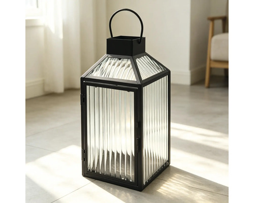 Schwarze Metalllaterne mit geriffelten Glaspaneelen und einem halbrunden Tragegriff, stehend auf einem hellen Fliesenboden.