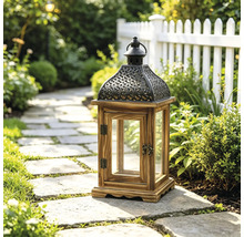 Lanterne de jardin décorative en bois et métal avec inserts en verre sur un chemin de pierre dans un jardin lumineux avec plantes et clôture.