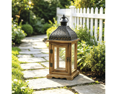 Lanterne de jardin décorative en bois et métal avec inserts en verre sur un chemin de pierre dans un jardin lumineux avec plantes et clôture.
