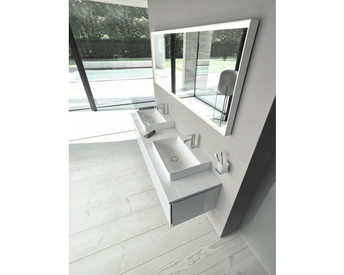 Modernes Badezimmer mit weißem Hängewaschtisch, zwei Aufsatzbecken, Armaturen und beleuchtetem LED-Spiegel. Heller Raum mit hellem Holzfußboden.