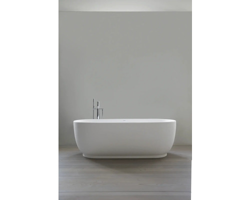 Baignoire îlot ovale au design moderne avec robinetterie de sol chromée et douchette à main dans une salle de bains claire et minimaliste.