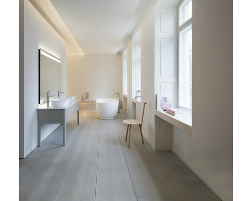 Salle de bains minimaliste et lumineuse avec baignoire en îlot blanche, double vasque à poser et parquet en bois clair.