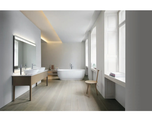 Salle de bain moderne et lumineuse avec double vasque, grand miroir, baignoire en îlot, sol en bois et grandes fenêtres.