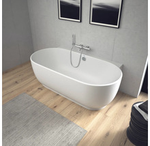Baignoire îlot ovale avec robinetterie murale en chrome dans une salle de bains moderne avec sol en bois et murs aspect béton.