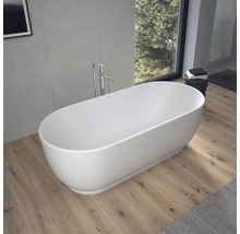 Baignoire îlot ovale dans une salle de bains moderne avec parquet, mur en béton et mitigeur sur pied.