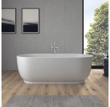 Baignoire îlot dans une salle de bains moderne avec sol en bois, mur en béton et robinetterie sur pied chromée.