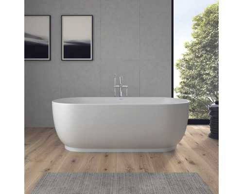 Baignoire îlot dans une salle de bains moderne avec sol en bois, mur en béton et robinetterie sur pied chromée.