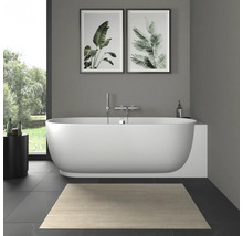 Salle de bains moderne avec baignoire en îlot ovale blanche, robinetterie murale, tableaux botaniques et tapis de bain clair.