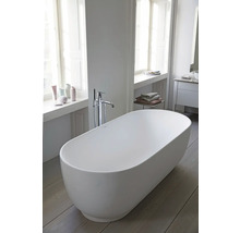 Baignoire îlot ovale dans une salle de bains moderne et lumineuse avec robinetterie au sol et parquet.