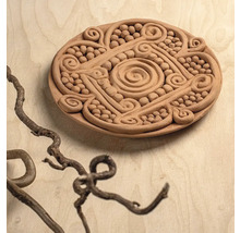 Runde Tonplatte mit handgefertigten Relief-Ornamenten wie Spiralen und Perlen.