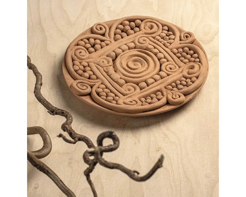 Runde Tonplatte mit handgefertigten Relief-Ornamenten wie Spiralen und Perlen.