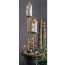 Dekorative Türme mit beleuchteten Fenstern, hängenden Sternen und Zapfen in einer rustikalen Nestbasis mit Grün und Vögeln.