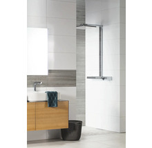 Modernes Badezimmer mit weißen und grauen Fliesen, Waschtischunterschrank in Holzoptik, weißem Aufsatzbecken und verchromter Regendusche.