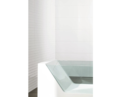Moderne Badewanne mit Glasseitenwand vor weiß gefliestem Hintergrund.