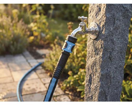 Textilschlauch mit for_q Logo an einem Außenwasserhahn an einer Steinsäule im Garten.