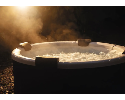 Spa gonflable rond avec eau bouillonnante, appuie-tête et vapeur montante en extérieur de nuit.