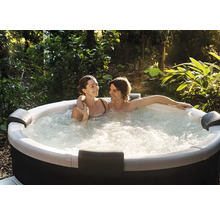 Un couple se détend dans un jacuzzi bouillonnant dans le jardin, entouré de plantes et de nombreux arbres.