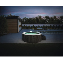 Jacuzzi gonflable Intex aspect bois foncé sur une terrasse moderne à côté d une piscine au crépuscule avec mobilier de jardin en arrière-plan.