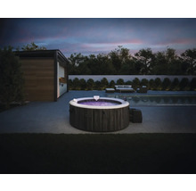 Spa gonflable Intex avec aspect pierre sur une terrasse moderne avec piscine et meubles de jardin au crépuscule.