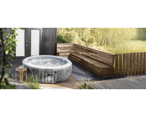 Spa gonflable Intex de forme ronde avec aspect bois sur une terrasse en bois à côté d'un banc d'angle en bois.