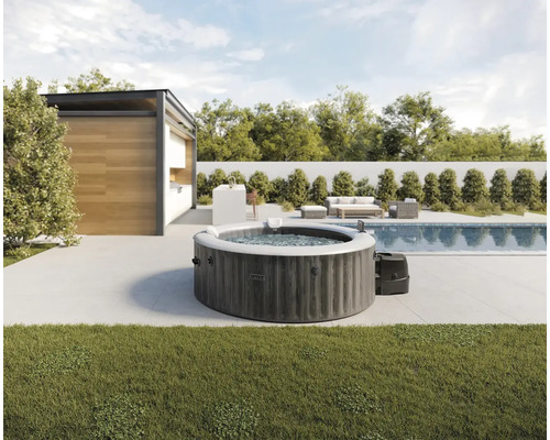 Spa gonflable rond Intex aspect bois sur une terrasse moderne à côté de la piscine et du pavillon de jardin.