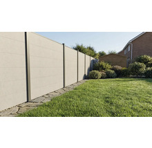 Clôture pare-vue moderne aspect béton avec poteaux métalliques dans un jardin avec pelouse et bordure en pierre.
