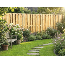 Ein gepflegter Garten mit einem Sichtschutzzaun aus Naturholzbrettern, einer Holzbank, Blumenbeeten mit Hortensien und einem Trittsteinpfad im Rasen.