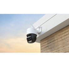 Caméra de surveillance extérieure sans fil montée sur le mur d'un bâtiment sous un avant-toit.