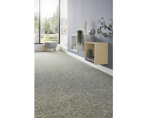 Texturierter Teppichboden in einem modern eingerichteten Wohnzimmer mit Wandregalen, Dekoration und einem großen Fenster mit Blick ins Grüne.