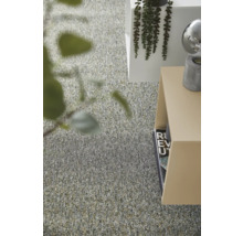 Moderner Innenraum mit texturiertem Teppichboden, minimalistischen Beistelltischen und dekorativen Grünpflanzen in einem hellen Raum.