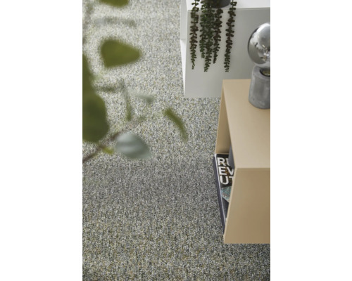 Moderner Innenraum mit texturiertem Teppichboden, minimalistischen Beistelltischen und dekorativen Grünpflanzen in einem hellen Raum.