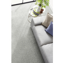 Moquette gris clair dans un salon moderne et lumineux avec canapé et tables basses rondes en verre.