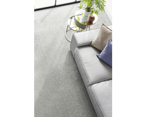 Moquette gris clair dans un salon moderne et lumineux avec canapé et tables basses rondes en verre.