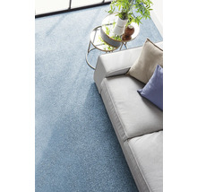 Moquette bleue texturée dans un salon lumineux avec un canapé gris et une table d'appoint en verre.