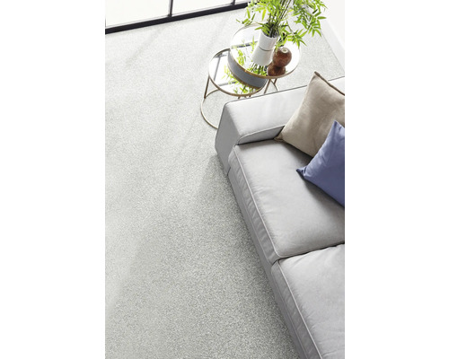 Moquette gris clair chinée dans un salon moderne et lumineux à côté d'un canapé et d'une table d'appoint avec une plante.